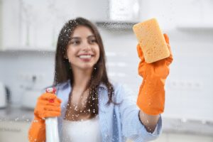 Beautiful woman washing window with detergent